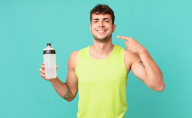 Spor salonundaki adam kendine güvenerek gülümsüyor. Kendi gülüşünü gösteriyor. Olumlu, rahat, tatmin olmuş bir tavır.