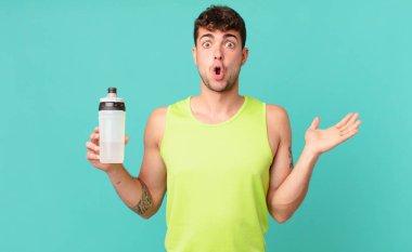 Fitness adam şaşırmış ve şaşırmış görünüyor, çene düşmüş bir obje açık bir el ile tutuyor