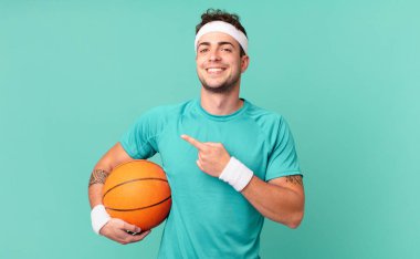 Fitness adamı heyecanlı ve şaşırmış görünüyor. Yana ve yukarıya bakıp boşluğu kopyalıyor.