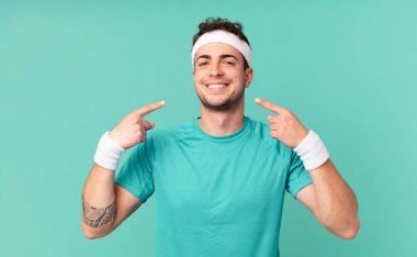 Spor salonundaki adam kendine güvenerek gülümsüyor. Kendi gülüşünü gösteriyor. Olumlu, rahat, tatmin olmuş bir tavır.