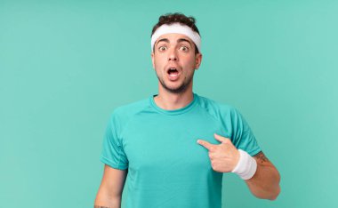 Fitness adamı şok olmuş ve ağzı açık, kendini işaret ederek şaşırmış görünüyor.