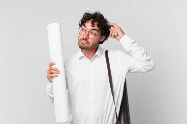 Mimar şaşkın ve şaşkın hissediyor, başını kaşıyor ve yana bakıyor.