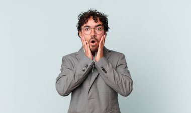 İspanyol işadamı şok olmuş ve korkmuş hissediyor, ağzı açık ve elleri yanaklarında korkmuş görünüyor.