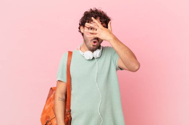 İspanyol öğrenci şok olmuş, korkmuş ya da korkmuş görünüyor. Yüzü elle kaplanmış ve parmaklarının arasından gizlice bakıyor.