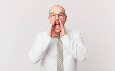 Kel iş adamı mutlu, heyecanlı ve pozitif hissediyor. Elleri ağızda, bağırarak bağırıyor.
