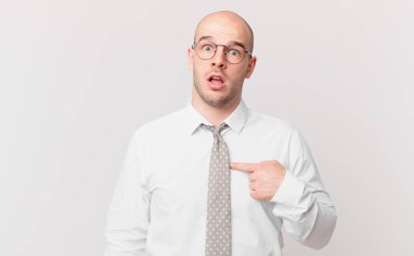 Kel işadamı ağzı açık, şaşkın ve şaşkın bir şekilde kendini işaret ediyor.