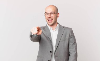 Kel iş adamı kameraya tatmin olmuş, kendinden emin, dostça bir gülümsemeyle bakıyor ve seni seçiyor.