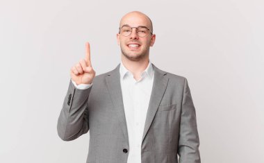 Kel işadamı gururla gülümsüyor ve gururla bir numaralı pozunu veriyor, kendini lider gibi hissediyor.