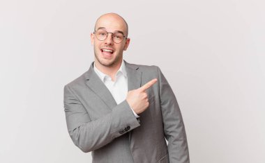 Kel işadamı heyecanlı ve şaşırmış görünüyor. Yana ve yukarı doğru göstererek boşluğu kopyalıyor.
