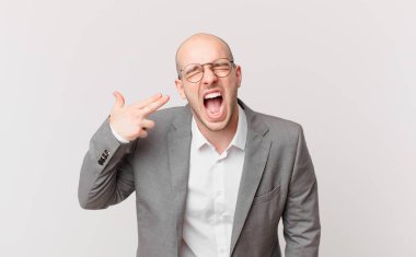 Kel işadamı mutsuz ve stresli görünüyor, intihar jesti silahla işaret ediyor, kafasını işaret ediyor.