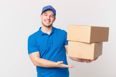 Paket teslim adam neşeli bir şekilde gülümseyerek, mutlu hissediyorum ve bir konsept göstermek fotokopi uzayda avuç içi ile
