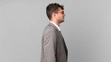 Profil görünümündeki işadamı ilerideki boşluğu kopyalamaya çalışıyor, düşünüyor, hayal ediyor ya da hayal kuruyor