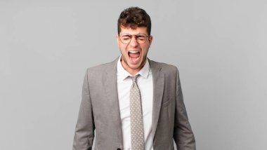 İş adamı bağırıyor, çok kızgın, hayal kırıklığına uğramış, öfkeli ya da sinirli görünüyor.