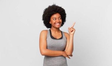 Siyah afro kadın mutlu bir şekilde gülümsüyor ve yan bakıyor, merak ediyor, düşünüyor ya da bir fikri var.