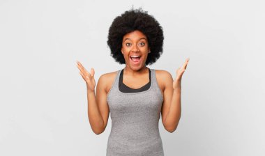 Siyah afro kadın mutlu, heyecanlı, şaşırmış ya da şok olmuş hissediyor, gülümsüyor ve hayrete düşüyor.