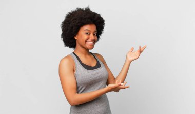 Siyah afro kadın gururla ve güvenle gülümsüyor, mutlu ve tatmin olmuş hissediyor ve fotokopi alanında bir konsept gösteriyor.