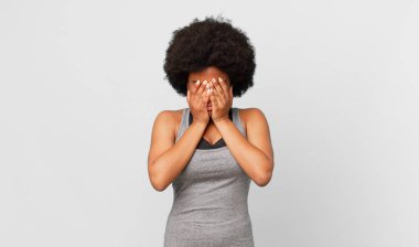 Siyah afro kadın üzgün, hayal kırıklığına uğramış, gergin ve depresif, iki eliyle yüzünü kaplayan, ağlayan