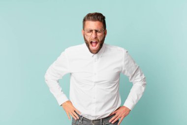 Genç yakışıklı adam agresif bir şekilde bağırıyor, çok sinirli görünüyor.