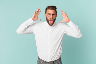 Genç yakışıklı adam ellerini havaya kaldırarak bağırıyor.