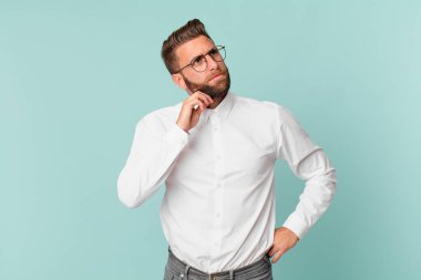 Genç yakışıklı adam düşünüyor, kuşkulu ve şaşkın hissediyor.