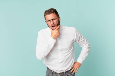 Ağzı ve gözleri açık ve eli çenesinde genç yakışıklı bir adam.