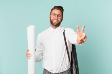 Genç yakışıklı adam gülümsüyor ve mutlu görünüyor, zafer ya da barış işareti yapıyor. mimar konsepti