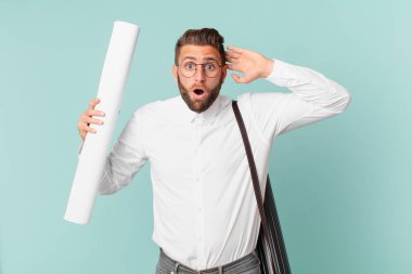 Genç yakışıklı adam mutlu, şaşkın ve şaşırmış görünüyor. mimar konsepti