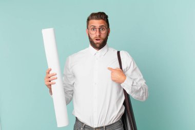 Genç ve yakışıklı bir adam mutlu hissediyor ve heyecanla kendini işaret ediyor. mimar konsepti