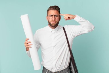 Genç yakışıklı adam kafası karışık ve şaşkın hissediyor, deli olduğunu gösteriyor. mimar konsepti