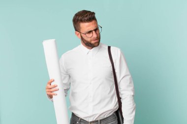 Genç ve yakışıklı bir adam üzgün, üzgün ya da kızgın hissediyor ve yan tarafa bakıyor. mimar konsepti