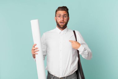 Şok olmuş ve ağzı açık, kendini işaret eden genç ve yakışıklı bir adam. mimar konsepti