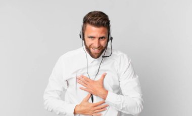 Genç yakışıklı bir adam komik bir şakaya yüksek sesle gülüyor. tele pazarlama kavramı