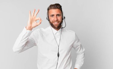 Genç yakışıklı adam kendini mutlu hissediyor, iyi bir jestle onaylıyor. tele pazarlama kavramı