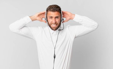 Genç ve yakışıklı bir adam stresli, endişeli ya da korkmuş hissediyor. Elleri başının üstünde. tele pazarlama kavramı