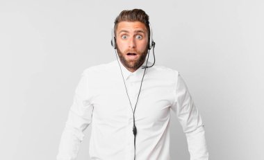 Genç ve yakışıklı bir adam çok şaşırmış ya da şaşkın görünüyor. tele pazarlama kavramı