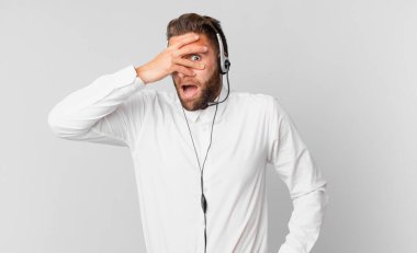 Genç, yakışıklı adam şok olmuş, korkmuş ya da korkmuş görünüyor. tele pazarlama kavramı