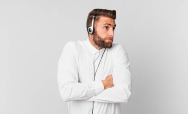 Genç yakışıklı adam omuz silkiyor, kafası karışık ve kararsız. tele pazarlama kavramı