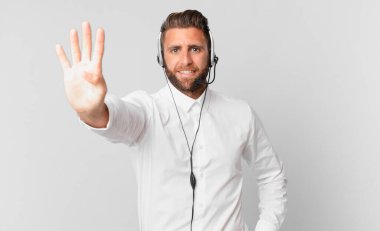 Genç yakışıklı adam gülümsüyor ve arkadaş canlısı görünüyor, dört numarayı gösteriyor. tele pazarlama kavramı