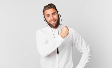 Genç yakışıklı adam kendini mutlu hissediyor ve bir meydan okumayla yüzleşiyor ya da kutluyor. tele pazarlama kavramı