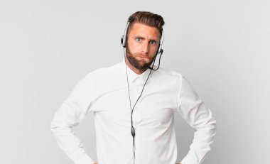 Kafası karışmış ve kafası karışmış genç yakışıklı bir adam. tele pazarlama kavramı