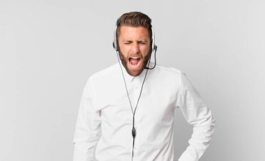 Genç yakışıklı adam agresif bir şekilde bağırıyor, çok kızgın görünüyor. tele pazarlama kavramı