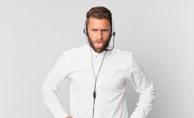 Genç ve yakışıklı bir adam tiksinmiş ve sinirlenmiş hissediyor ve dilini dışarı çıkarıyor. tele pazarlama kavramı