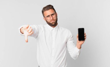 Genç ve yakışıklı bir adam kendini kötü hissediyor, baş parmağını kaldırıyor ve hücresini tutuyor.