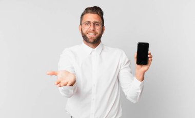 Genç yakışıklı adam mutlu bir şekilde gülümsüyor ve bir konsept sunuyor ve bir hücre tutuyor.