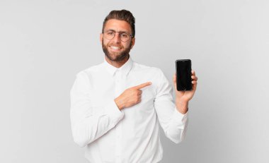 Genç yakışıklı adam neşeyle gülümsüyor, mutlu hissediyor ve bir hücreyi işaret ediyor.