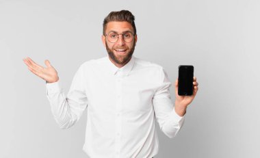 Genç yakışıklı adam mutlu, şaşırmış bir şekilde çözümü ya da fikri fark ediyor ve hücreyi tutuyor.