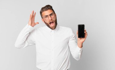 young handsome man screaming with hands up in the air and holding a cell