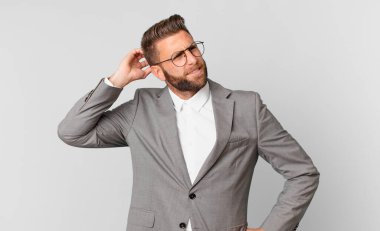 Kafası karışmış, kafası karışmış, kaşınan genç, yakışıklı bir adam. iş kavramı