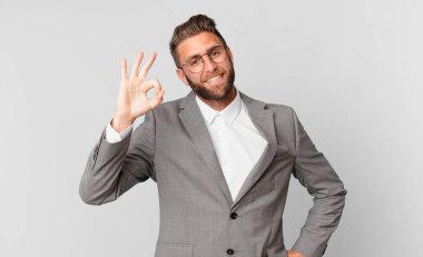 Genç yakışıklı adam kendini mutlu hissediyor, iyi bir jestle onaylıyor. iş kavramı