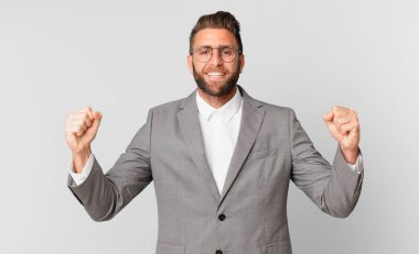 Genç yakışıklı adam şok olmuş hissediyor, gülüyor ve başarıyı kutluyor. iş kavramı